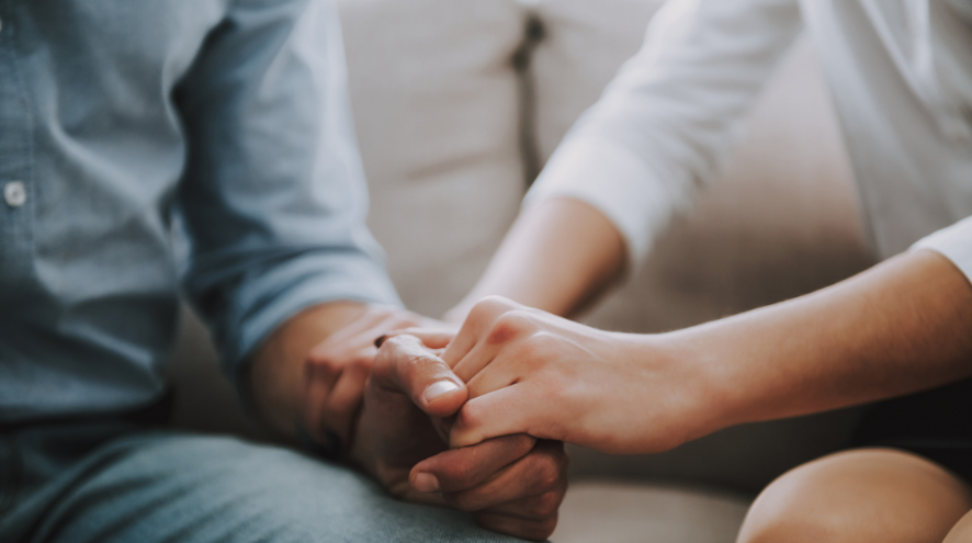 woman supportingly holding man's hand